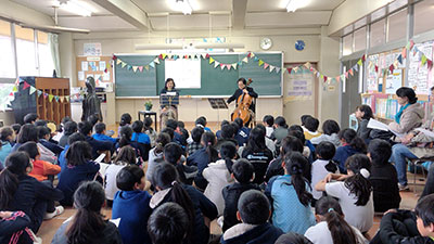 教室で朗読とチェロの演奏を聴く生徒たち